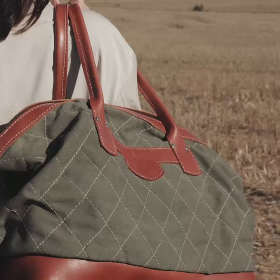 A green and brown leather overnight bag with a quilted design, featuring a shoulder strap and a handle. Handcrafted in Cape Town