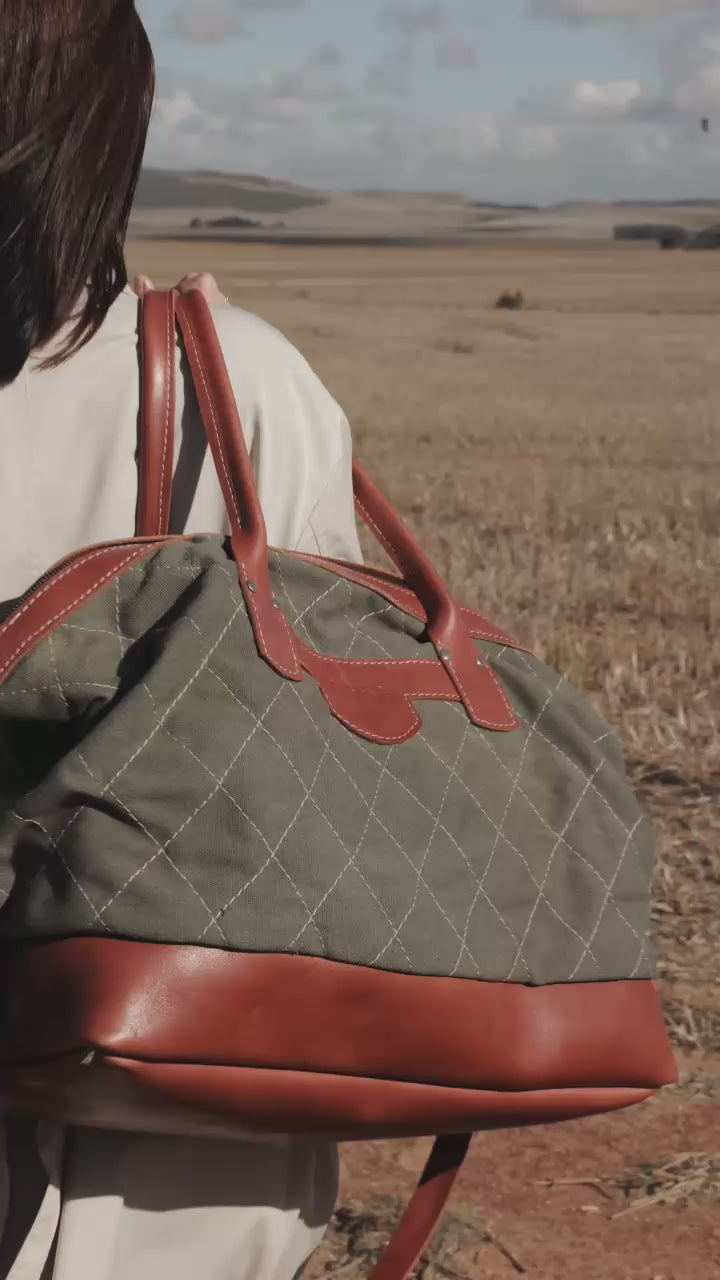 A green and brown leather overnight bag with a quilted design, featuring a shoulder strap and a handle. Handcrafted in Cape Town